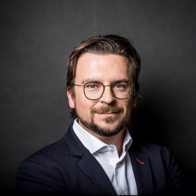 KI_Park Ein europäischer Mann mit Brille posiert für ein Foto in einem Innovationsökosystem.