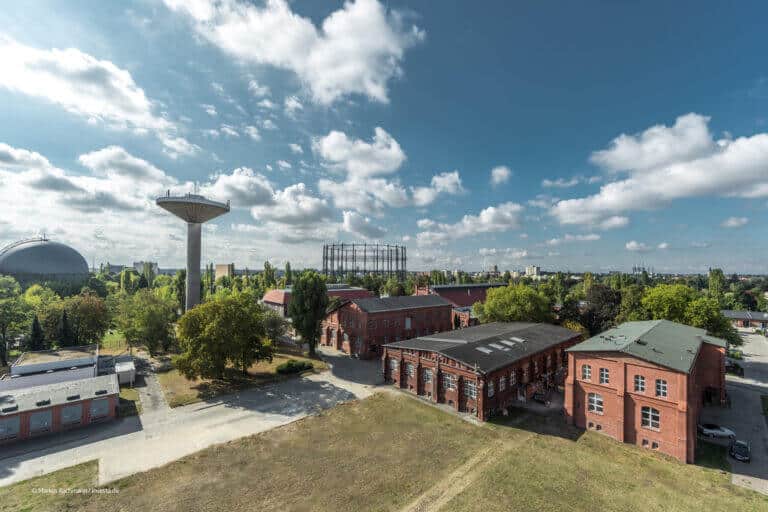 KI_Park Eine Luftaufnahme eines alten Gebäudes mit einem Wasserturm im Hintergrund, der das KI-Flaggschiff zeigt.