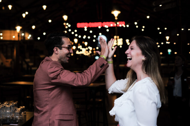 KI_Park Ein Mann und eine Frau geben sich während eines KI-Workshops in einer Bar gegenseitig High Fives.